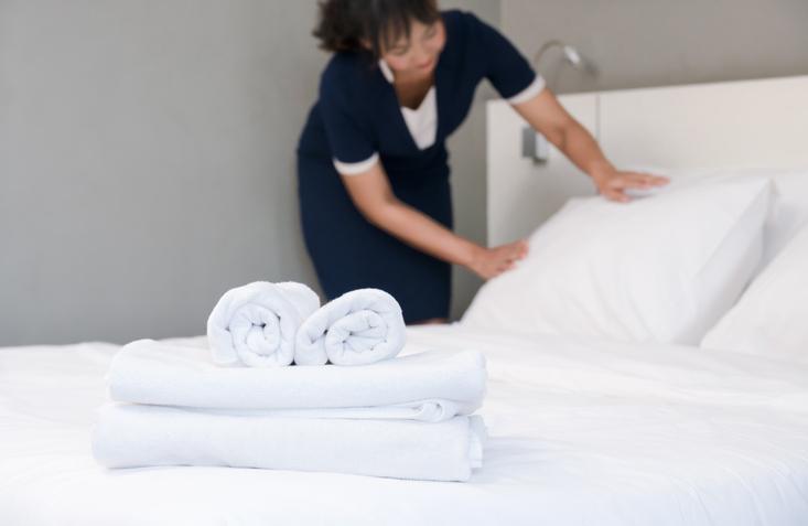 Hotel staff is properly cleaning the bed for incoming guests.